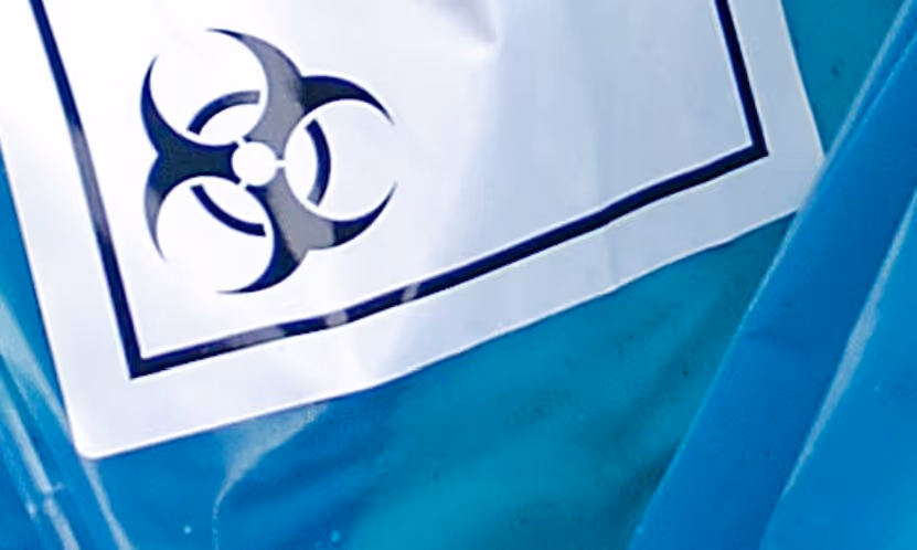 Blue medical hazardous waste bags with biohazard labels for healthcare disposal and specialized hauling services