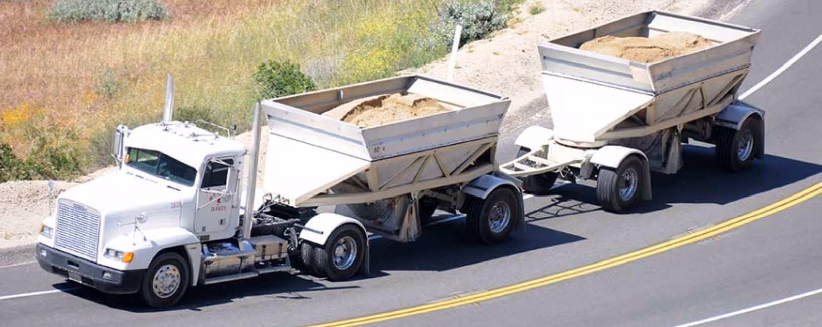 White double bottom dump truck with dual trailers for maximum capacity commercial material hauling services