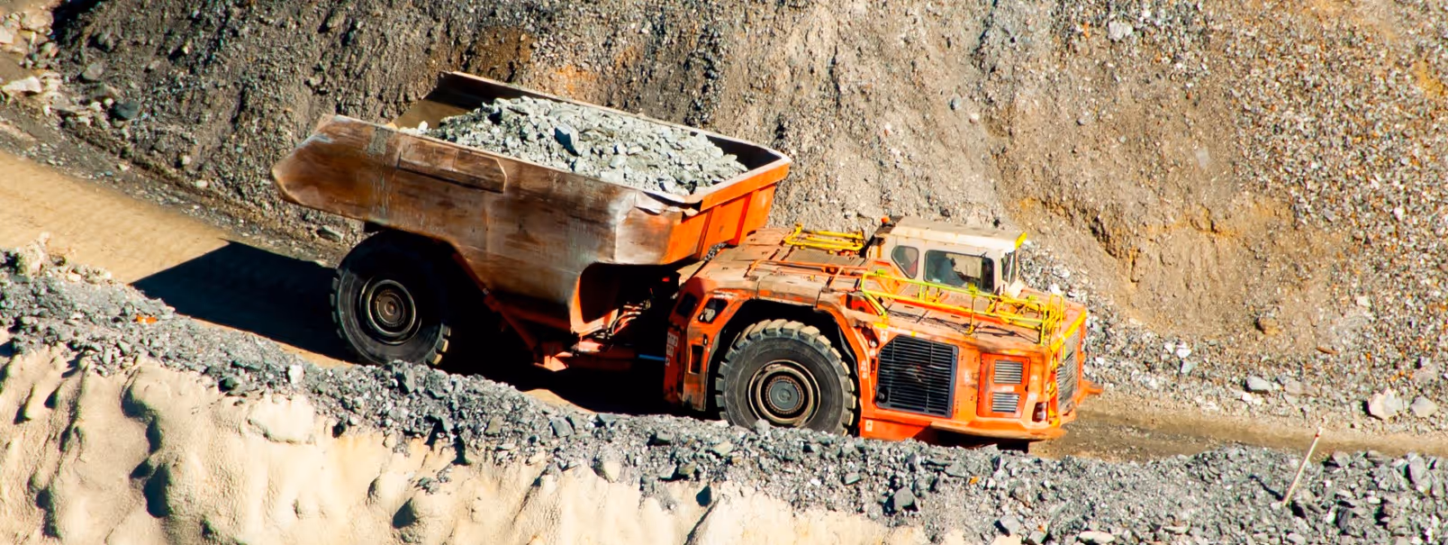 Orange underground dump truck for mining operations and specialized underground material hauling services