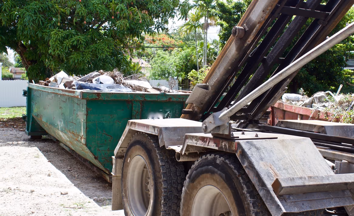 Roll-off truck with green dumpster for commercial waste removal and construction debris hauling services
