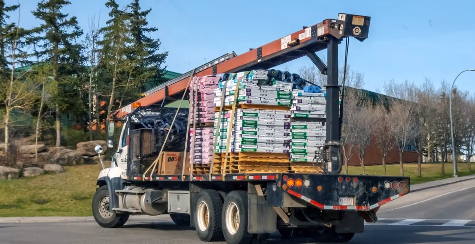 White utility truck with crane and building materials for commercial construction supply and service delivery