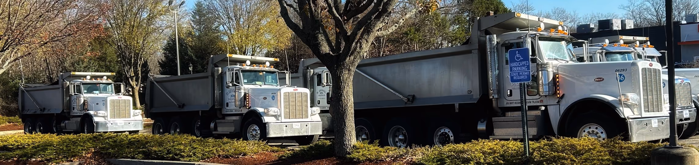 Fleet of white construction material trucks with dump beds in Springfield, Massachusetts
