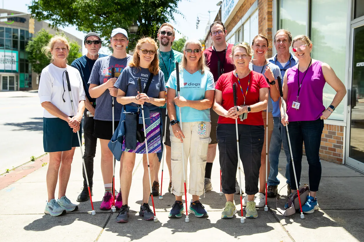A group of The Maryland School for the Blind staff smiling with white canes