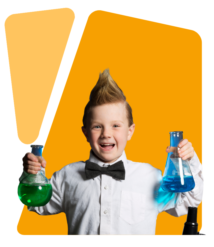 Smiling boy with a mohawk hairstyle wearing a white shirt and black bow tie, holding a green liquid in a round flask and a blue liquid in a conical flask.