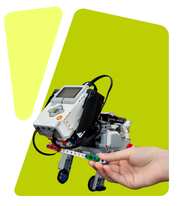 Hand holding a small robot made from Lego Mindstorms components against a green abstract background.