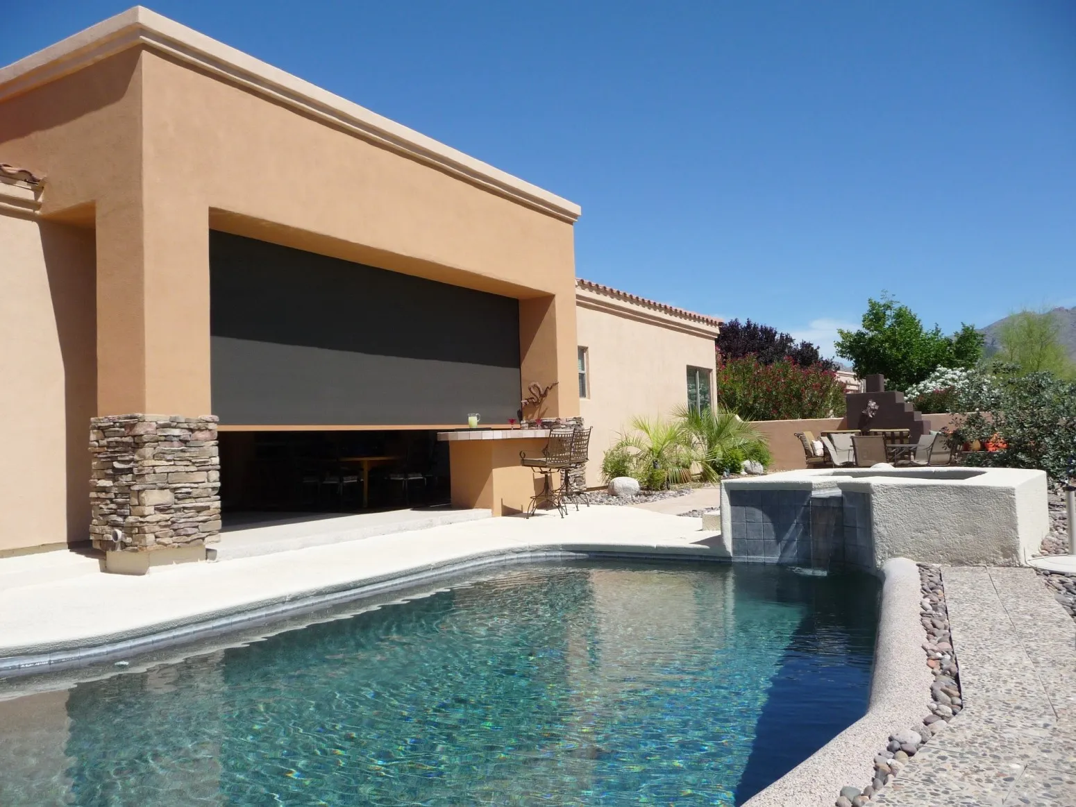 Solar screens partially deployed by the pool