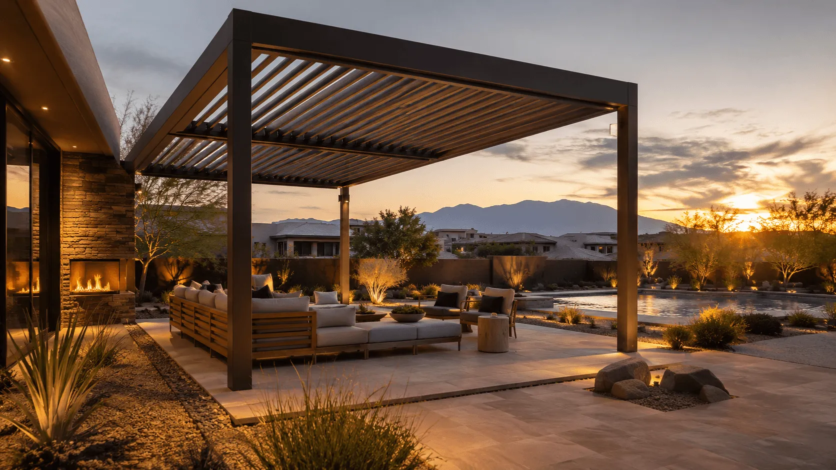 Louvered pergola over an outdoor lounge with a fireplace, next to a pool at sunset in the desert