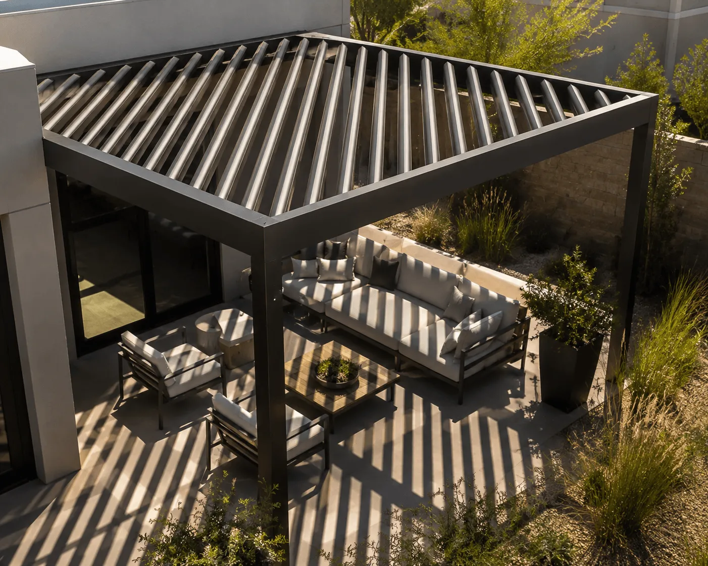 Elevated view of a louvered pergola casting striped shadows over a patio seating area