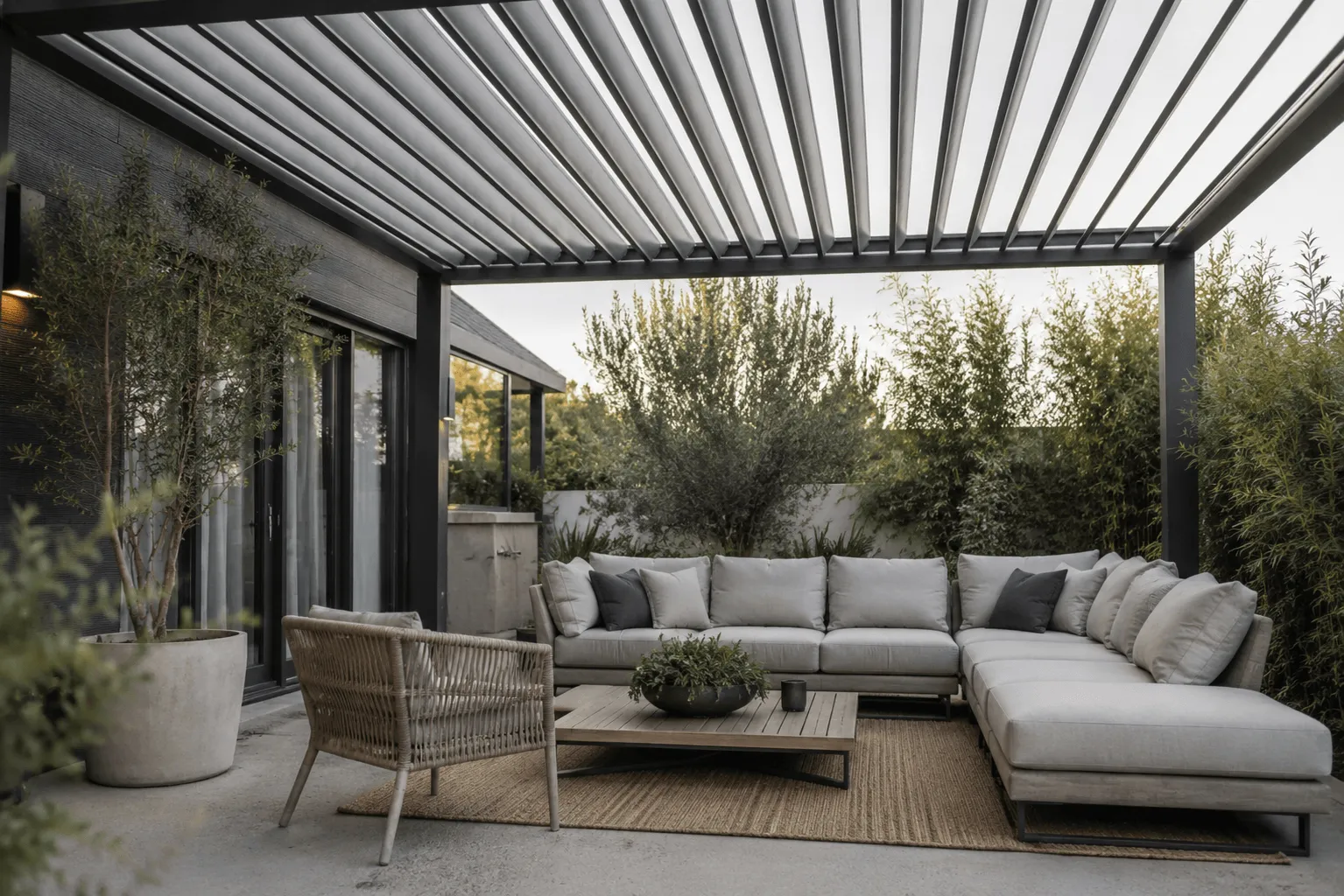 Close-up of open louvered pergola slats attached to a dark house exterior with greenery beyond