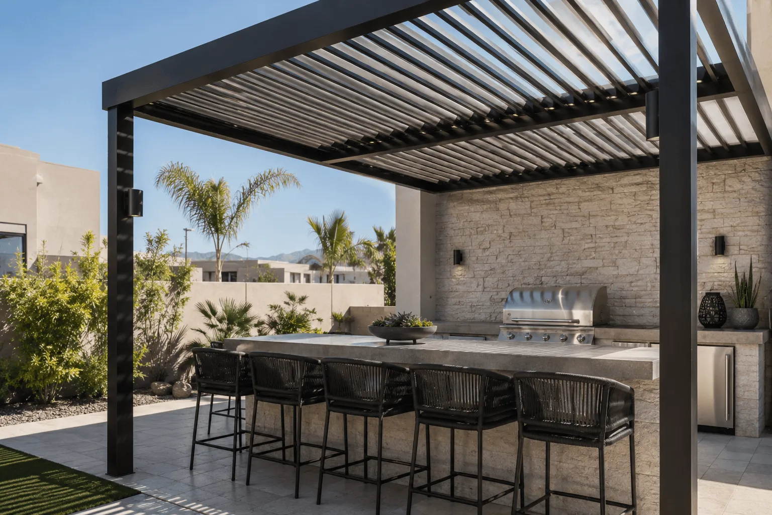 Louvered pergola covering an outdoor kitchen with a built-in grill, stone bar, and seating