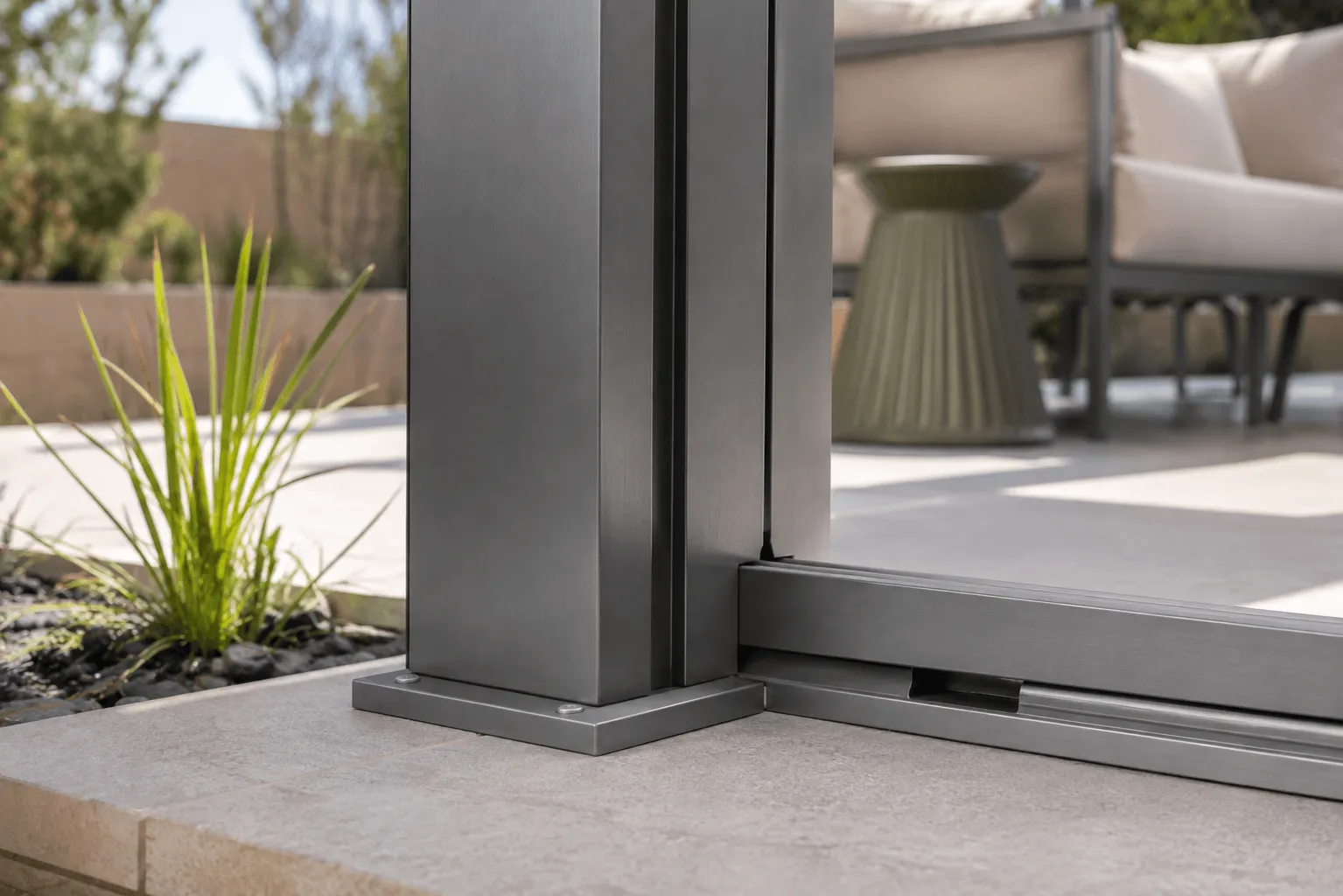 Close-up of a pergola's aluminum post base and integrated sliding door track on a patio