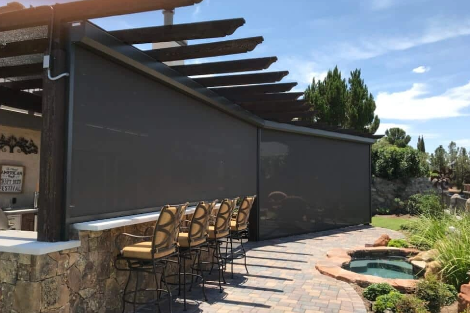 Outdoor patio with motorized screens and bar seating under pergola in Las Vegas.