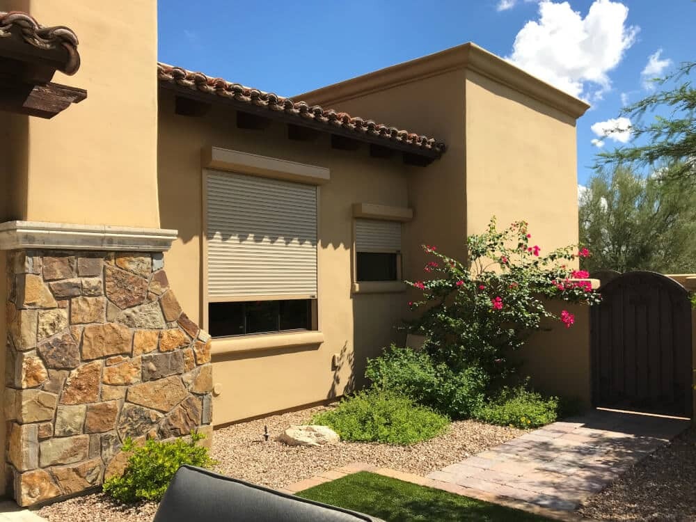 Partially closed rolling shutters installed over windows on a desert home