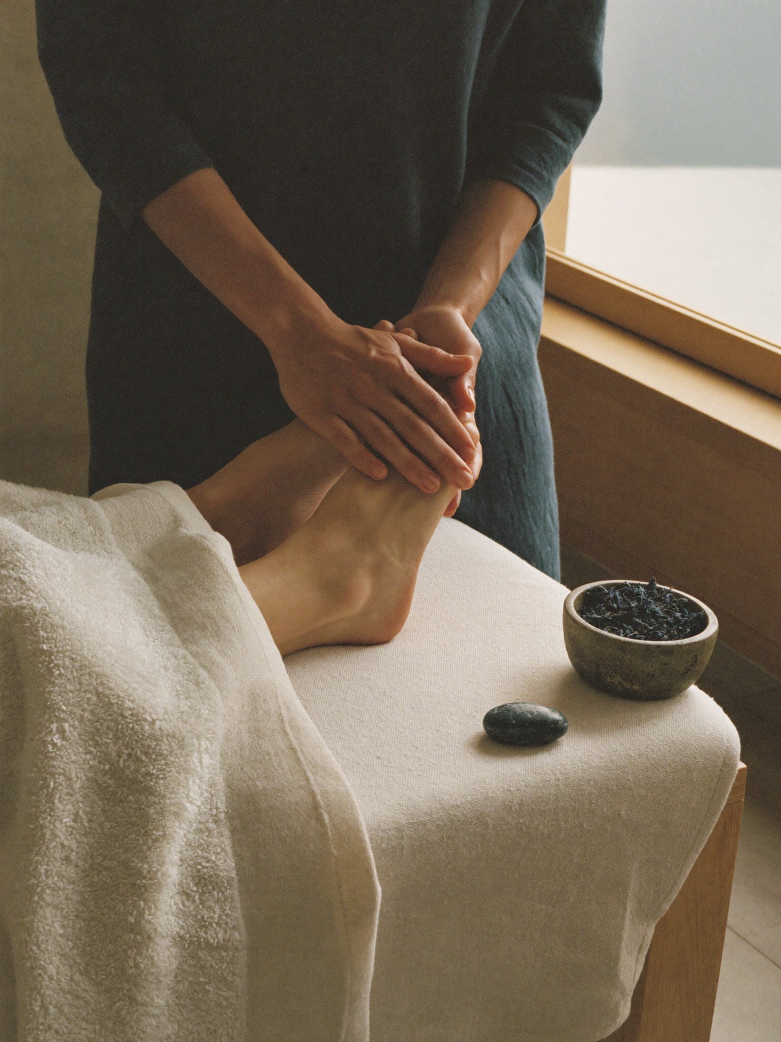 Therapist holding a guest's feet in a grounding hold during a holistic treatment