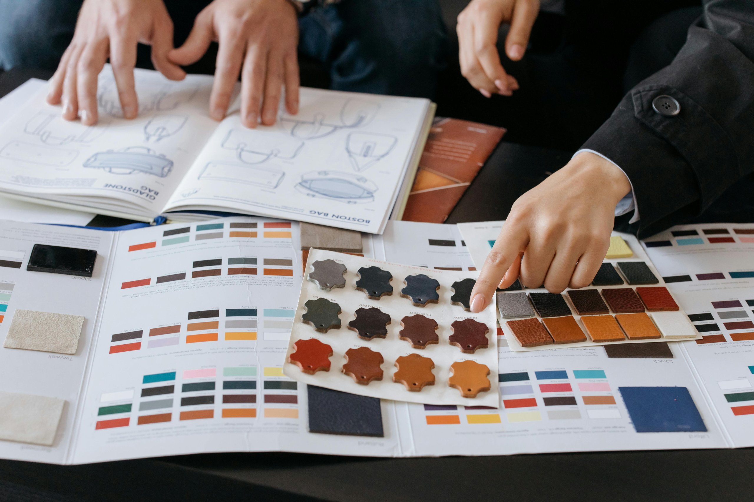 Two hands reviewing color and material samples on a table with sketches and swatches.