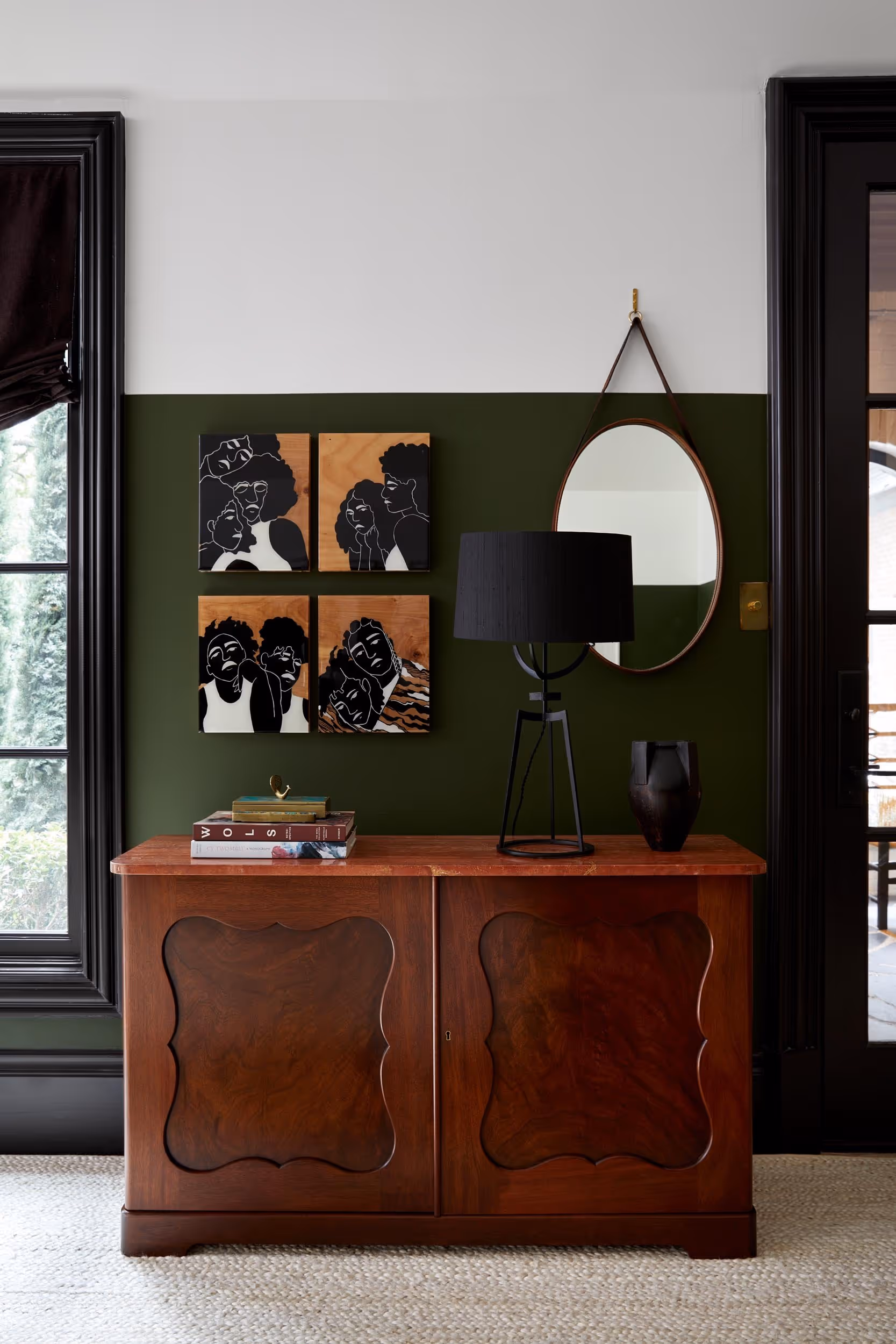 Wood dresser with decor on top and a painting and oval mirror mounted on the wall its against