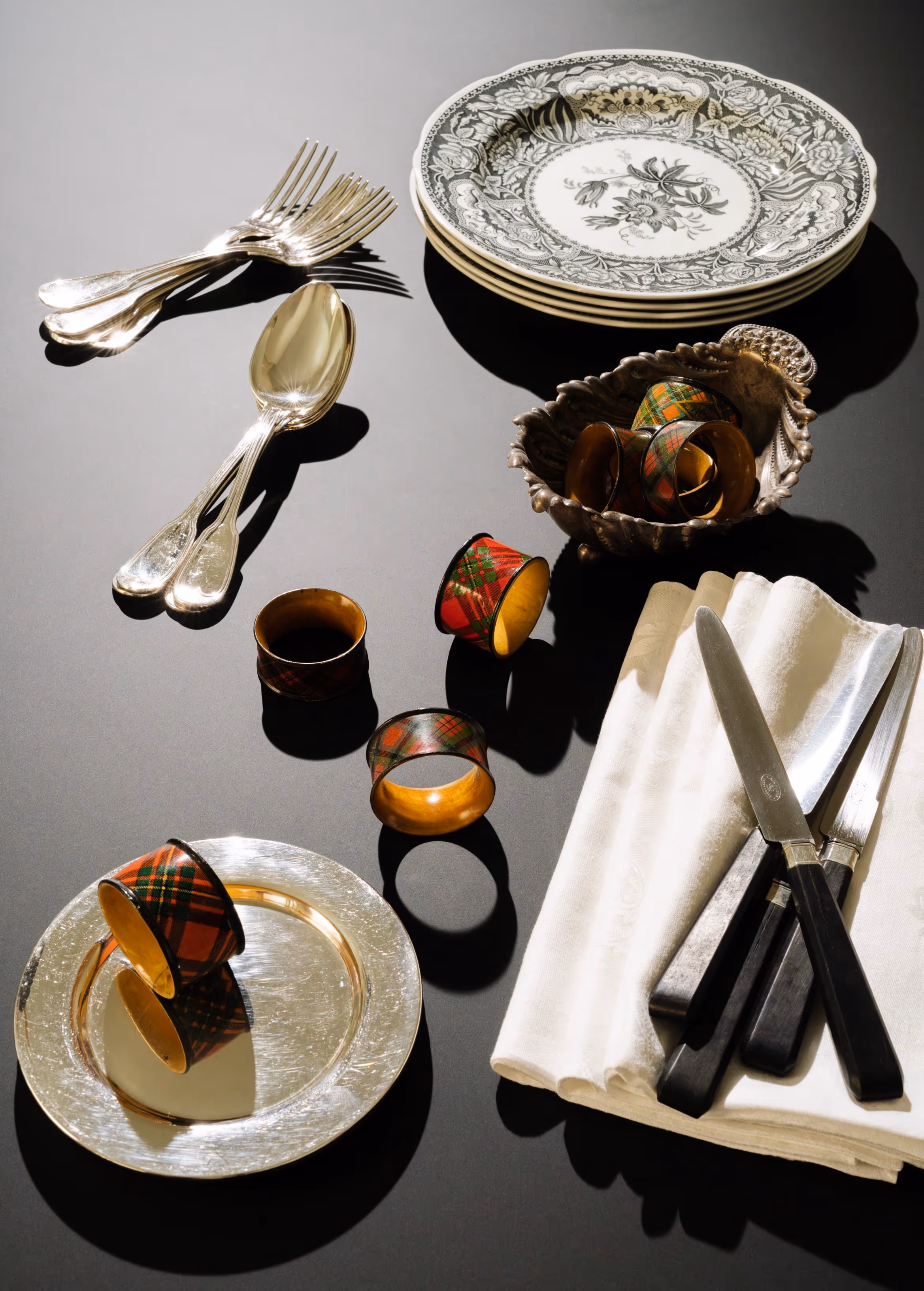 Table scape with stack of plates, utensils, napkins, and napkin rings