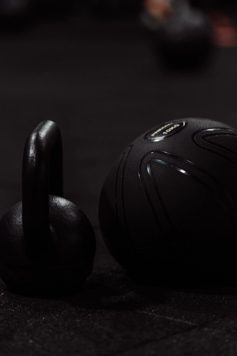 A black kettlebell and a black ball resting on the gym floor at Unity Personal Training in Grays, ENG.