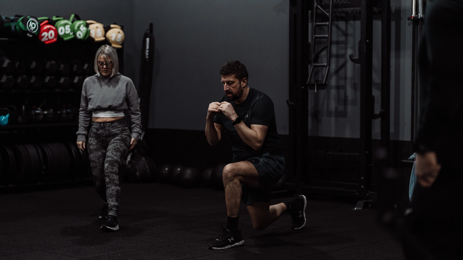 A man and woman squatting together in a gym during a fitness class at Unity Personal Training in Grays, ENG.