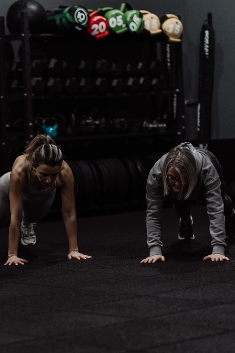 A group of individuals performing push-ups in a gym during a Team Strength & Conditioning session at Unity Personal Training, Grays.