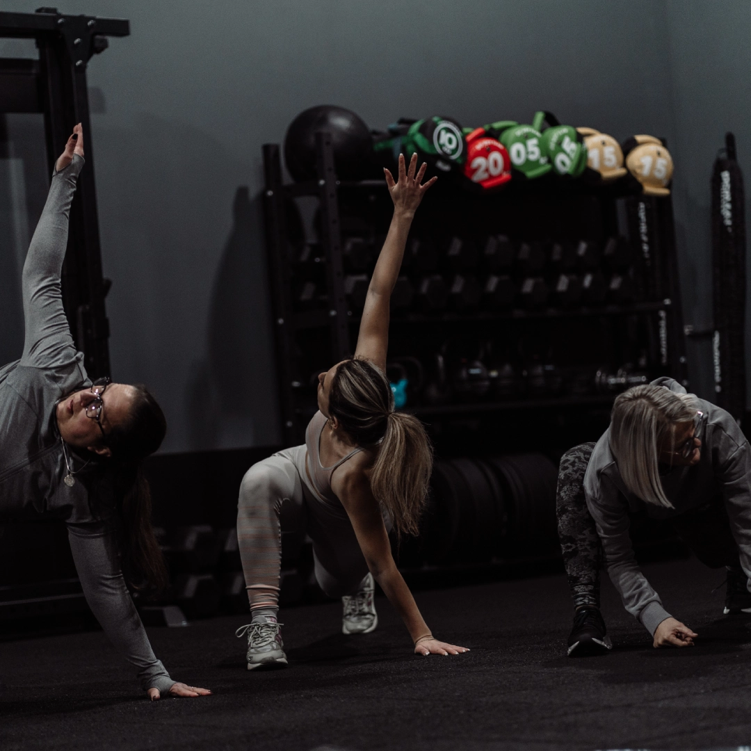 Three women performing push-ups in a gym at Unity Personal Training in Grays, England.