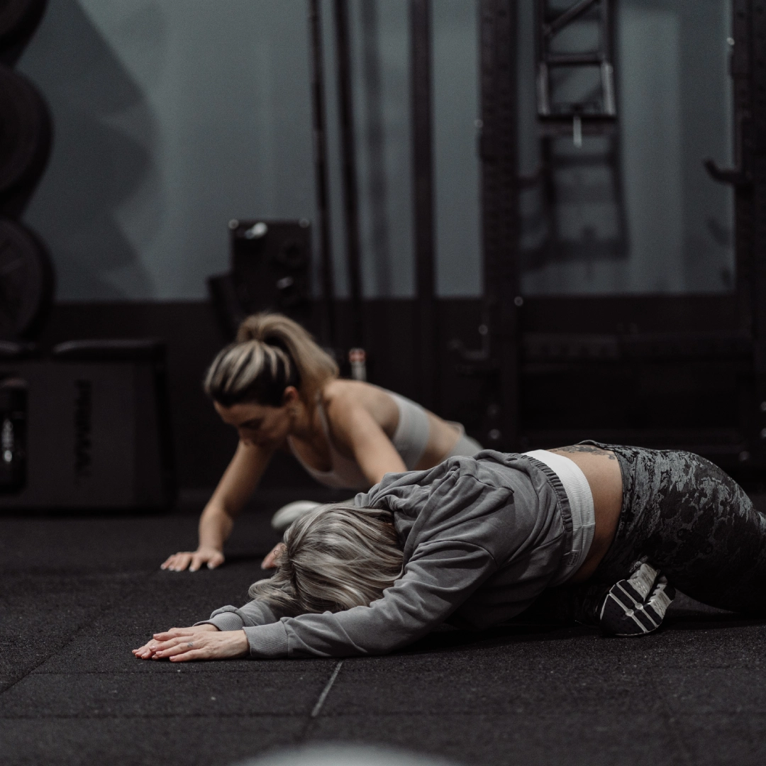 Two women performing push-ups on the floor at Unity Personal Training in Grays, England.