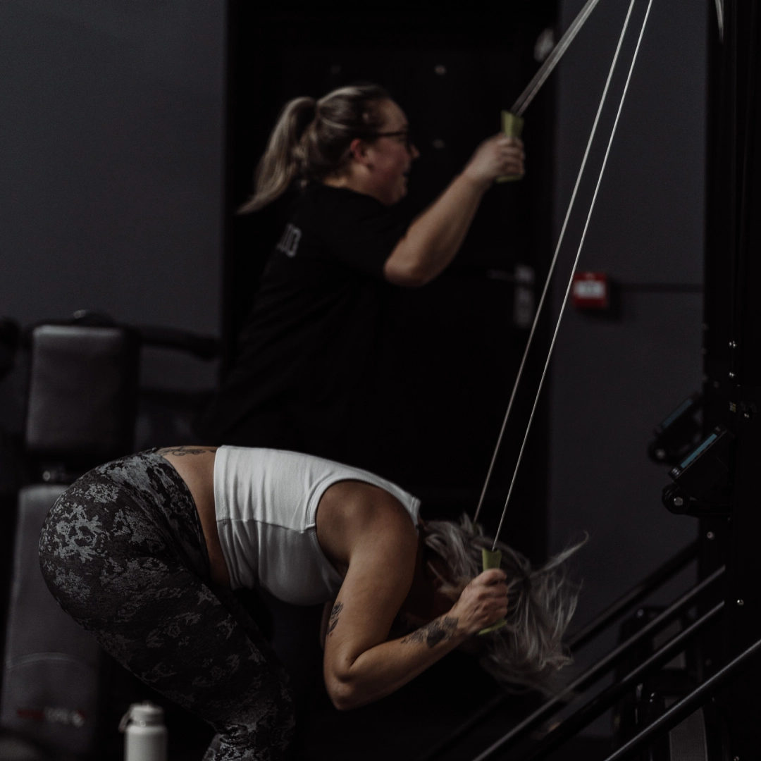 A woman performs a pull-up on a bar at Unity Personal Training in Grays, ENG, showcasing strength and fitness.