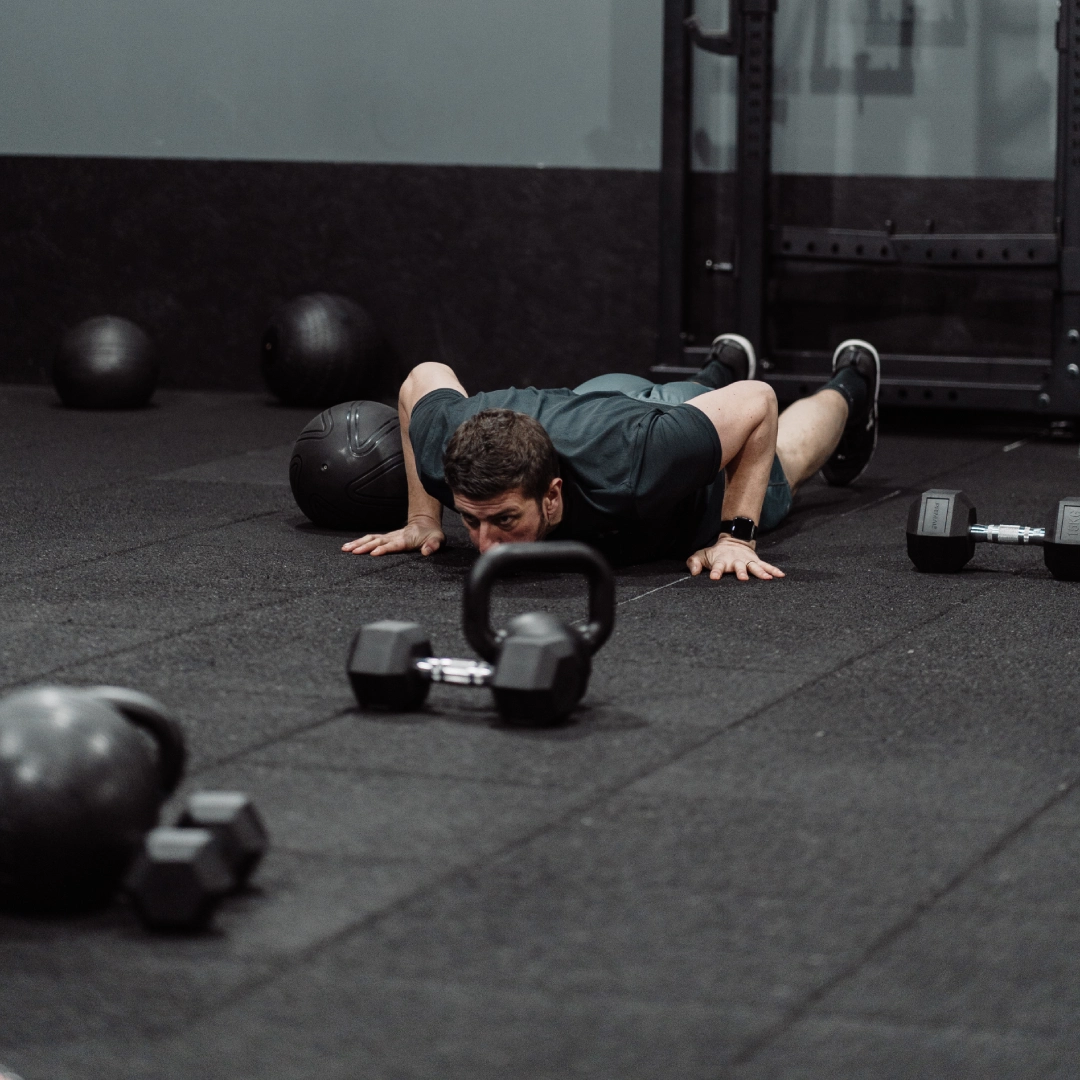 A man lies on the floor with dumbbells at Unity Personal Training in Grays, ENG, focusing on his workout routine.