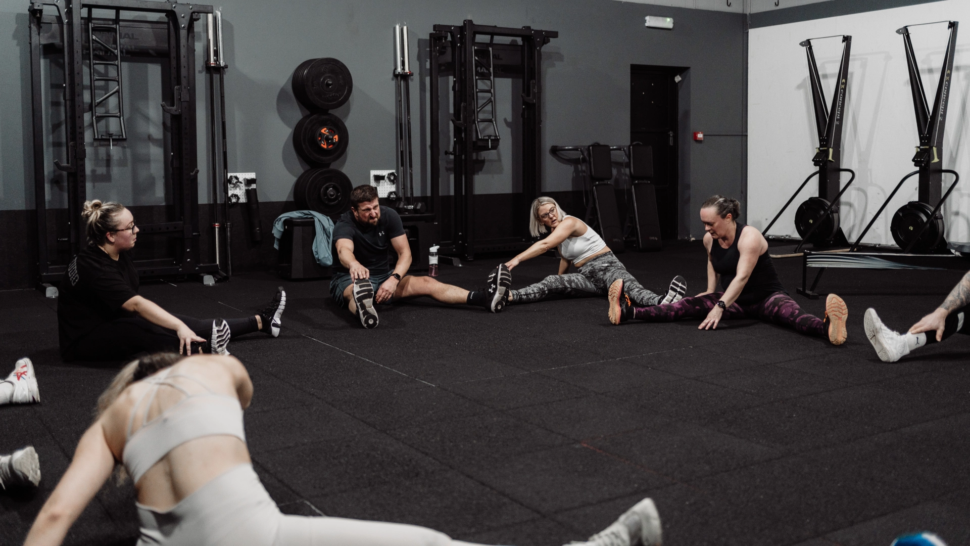 A group of people sitting on the gym floor at Unity Personal Training in Grays, ENG, engaged in a fitness session.