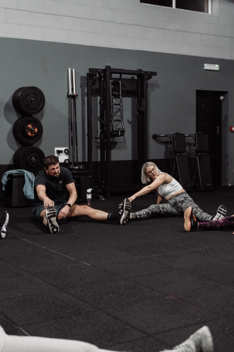 A group of people sitting on the gym floor at Unity Personal Training in Grays, ENG, engaged in a fitness session.