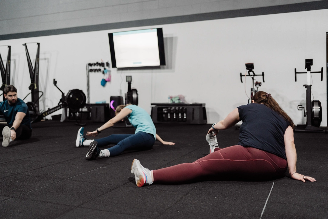 A group of people sitting on the gym floor at Unity Personal Training in Grays, ENG, engaged in a fitness session.
