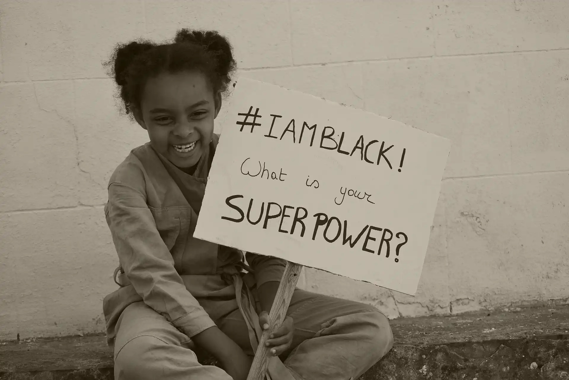 a young black girl holds a sign that says I am black, what is your superpower?