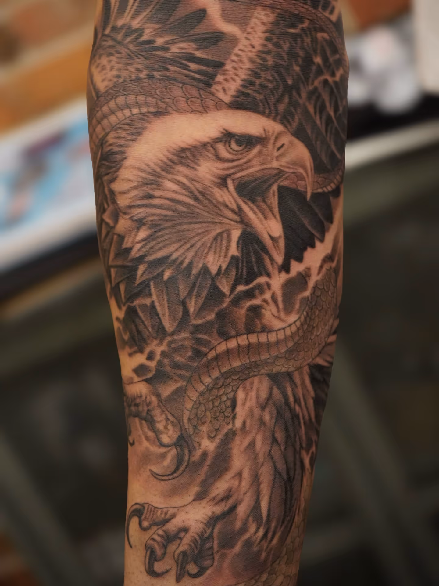 Black and grey forearm tattoo of an eagle attacking a snake