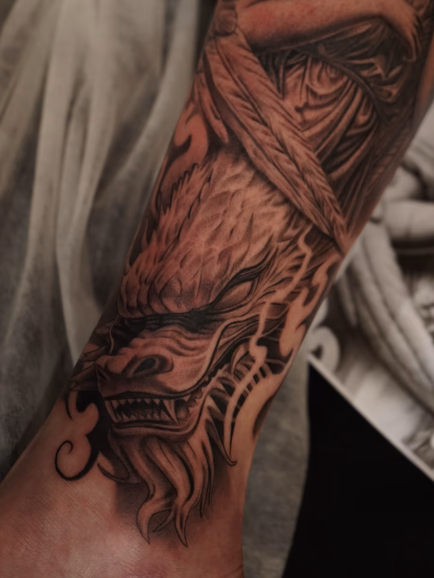 Black and gray snarling wolf head tattoo on the lower leg with detailed shading.
