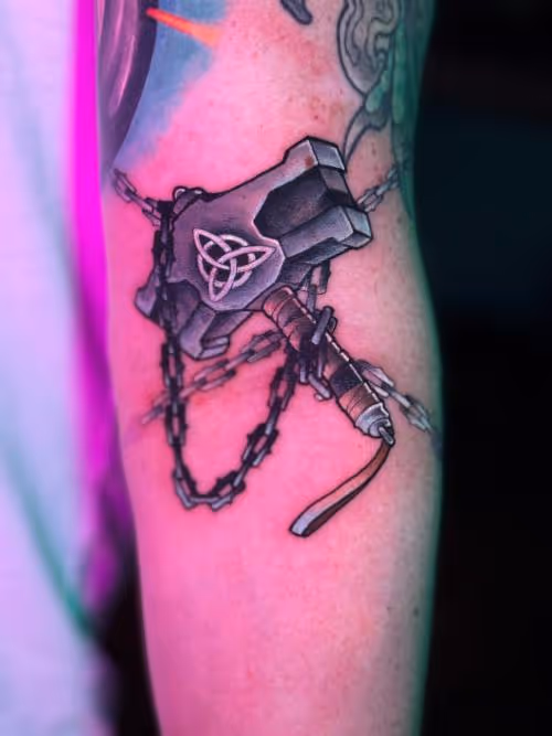 Forearm tattoo of a chained hammer with a Celtic triquetra knot.