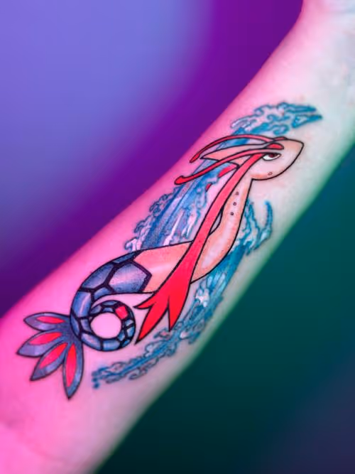 Colorful forearm tattoo of Pokémon Milotic with flowing red fins and blue waves