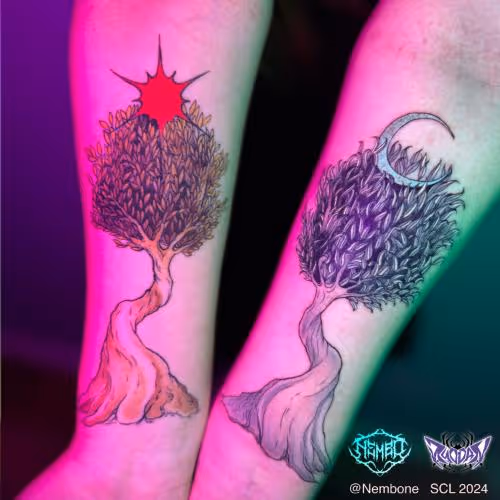 Matching forearm tattoos of twisted trees with a red sun and a crescent moon.