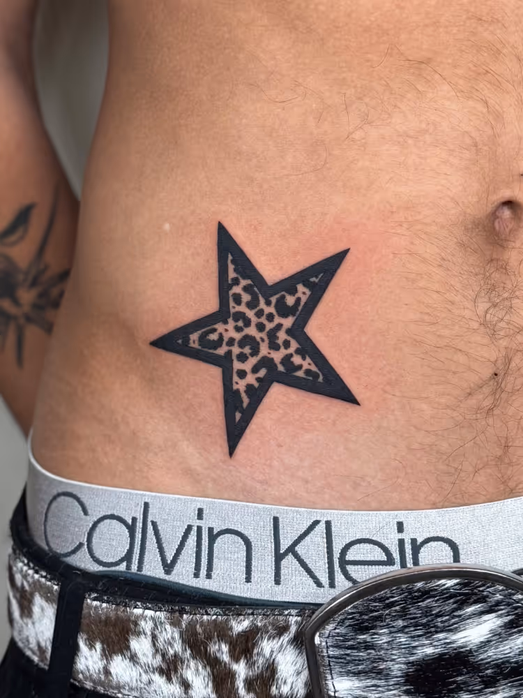Leopard-print star tattoo on lower abdomen near hip
