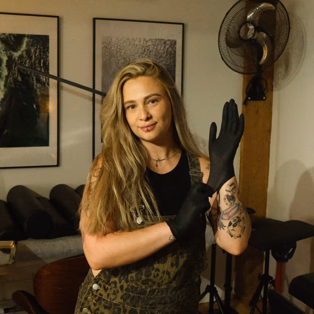 Tattoo artist putting on black gloves in a studio.