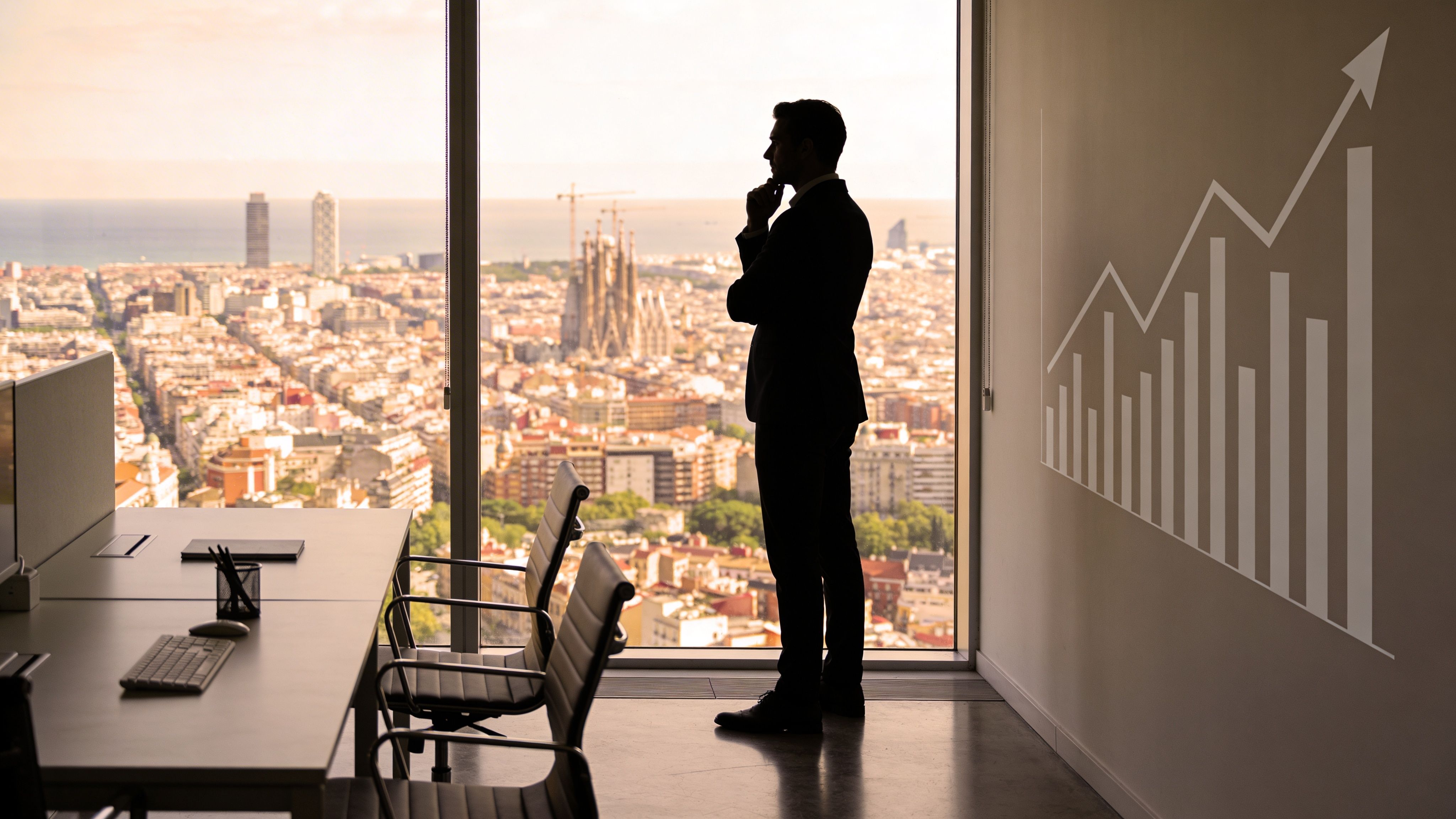Un ejecutivo observa la ciudad de Barcelona desde una oficina moderna con un gráfico de crecimiento profesional.