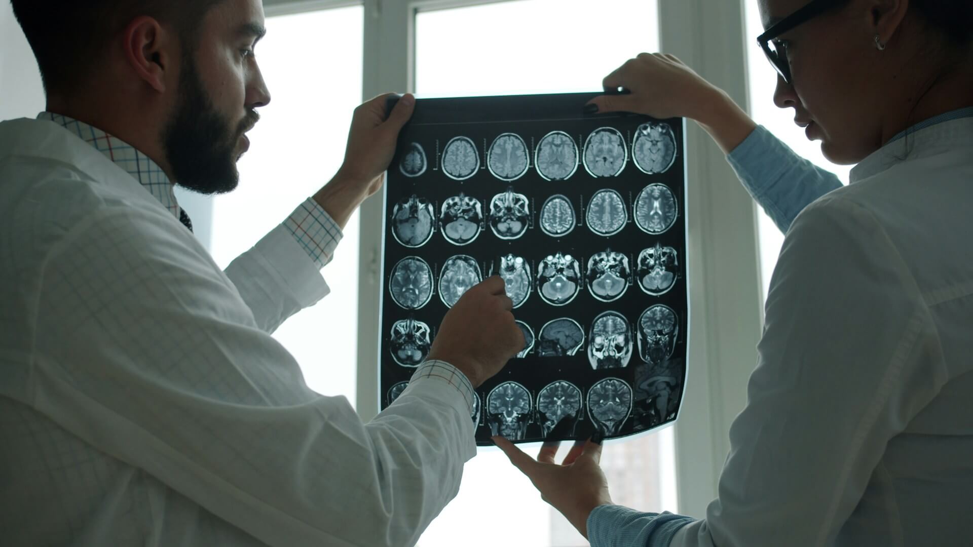 Illustrasjonsbilde av to forskere som studerer nevroavbildning av en hjerne, brukt for å representere forskning på visuell prosessering ved Irlen-syndrom.