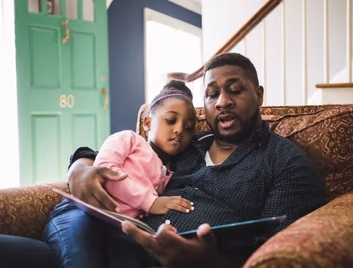 Daughter and father reading a book together 