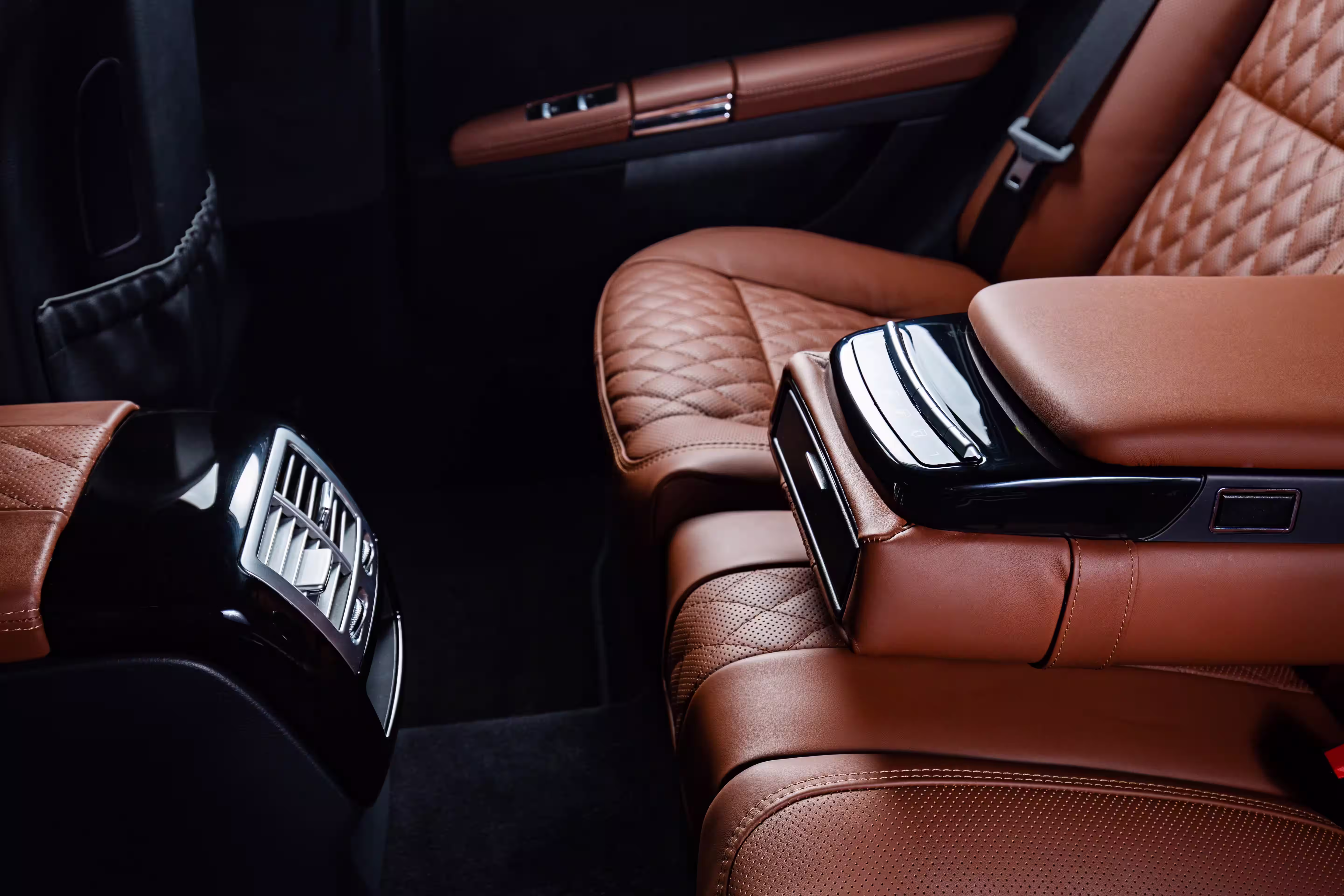 Interior view of a luxury car seat with brown leather upholstery and a center console featuring controls. The design showcases a quilted pattern on the seat and a sleek look for professional car care. Keywords: Mobile, Autoreinigung, Zürich, Professionelle Autopflege.