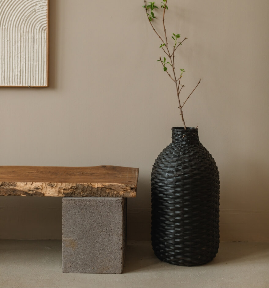 Refined interior of a home with a natural wooden bench with cement legs and a black vase