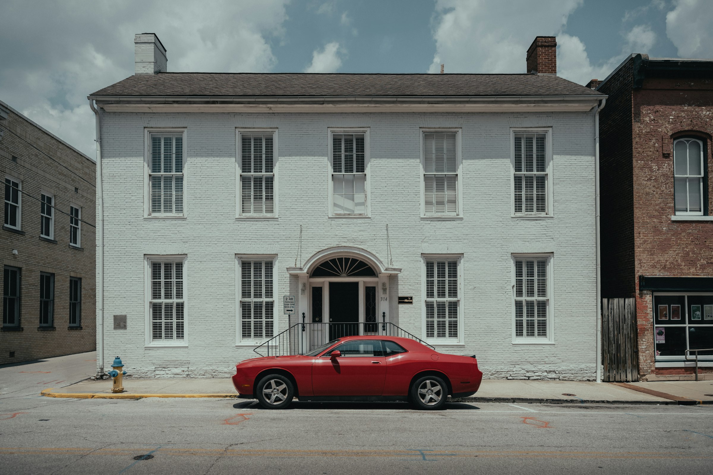 Red car parked in front of a white historic building in Frankfort, Kentucky