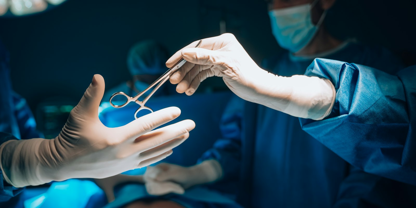 Surgeon handing over instruments in an operating room, the kind of high-earning professional who cannot realistically qualify for REPS