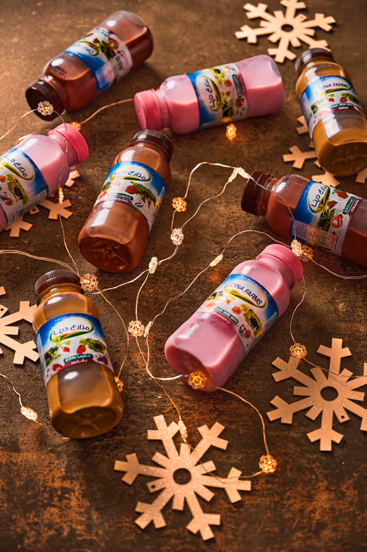 Photo of Dina Farms chocolate and strawberry milk bottles laying on the floor surrounded by christmas decorations