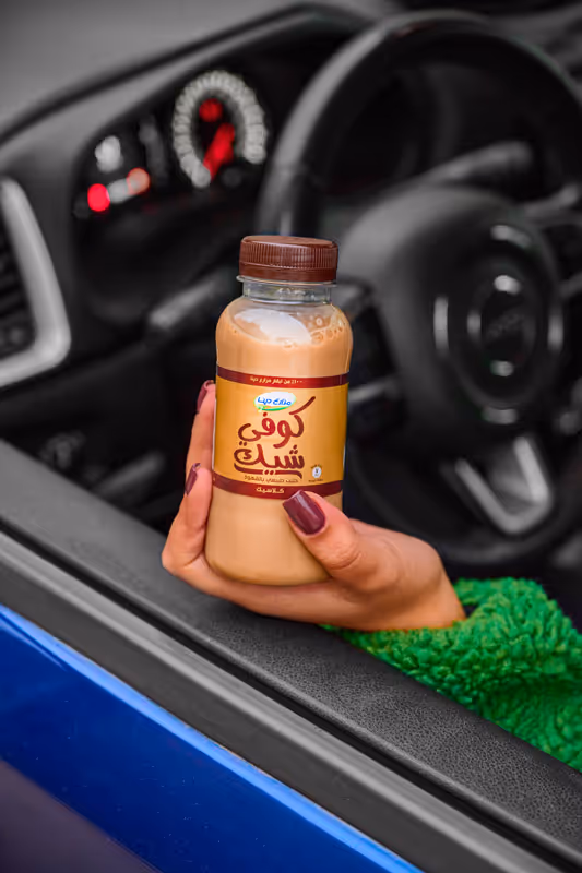 Photo of a lady in a car holding a bottle of Dina Farms Coffee Shake