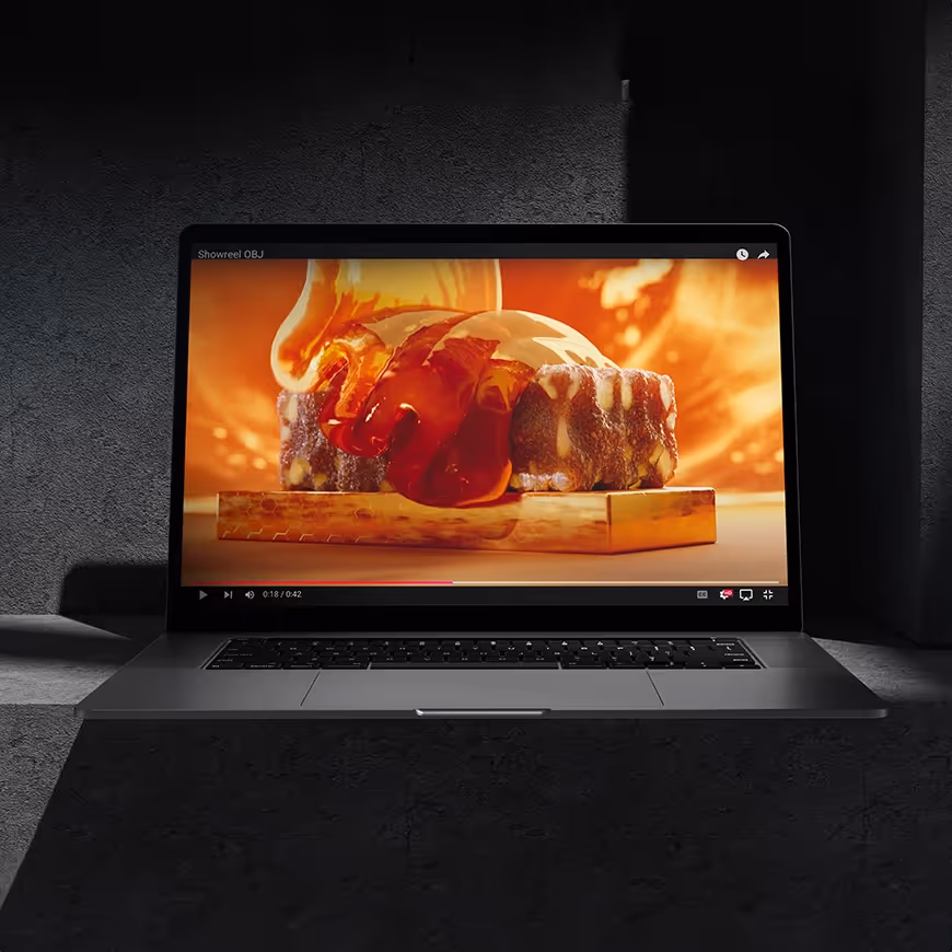 Laptop screen shows molten liquid over a sculpted object with fiery tones, symbolising the precision of editing videography.