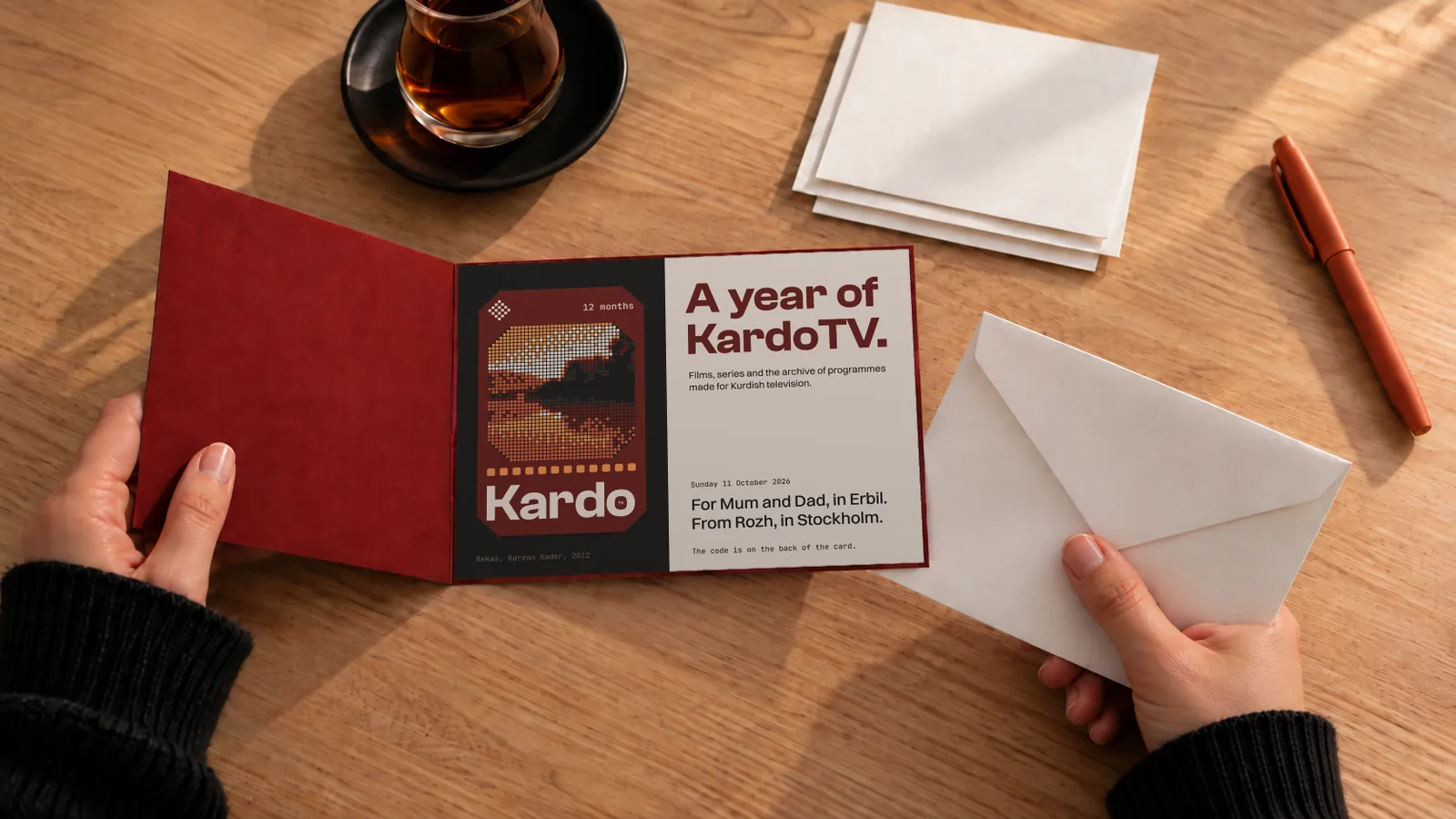 A card reading A year of KardoTV pulled from its envelope beside a glass of tea